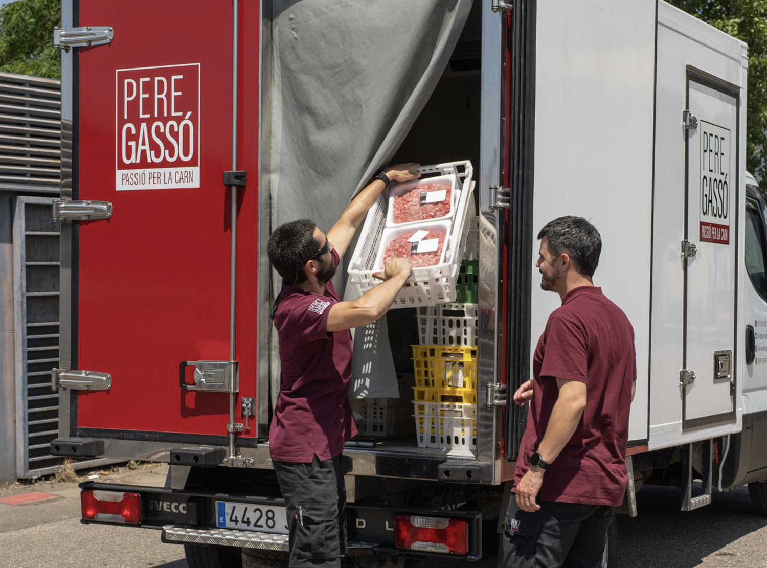 Treballadors de Pere Gassó carregant productes carnis al camió refrigerat per garantir un repartiment segur i puntual.